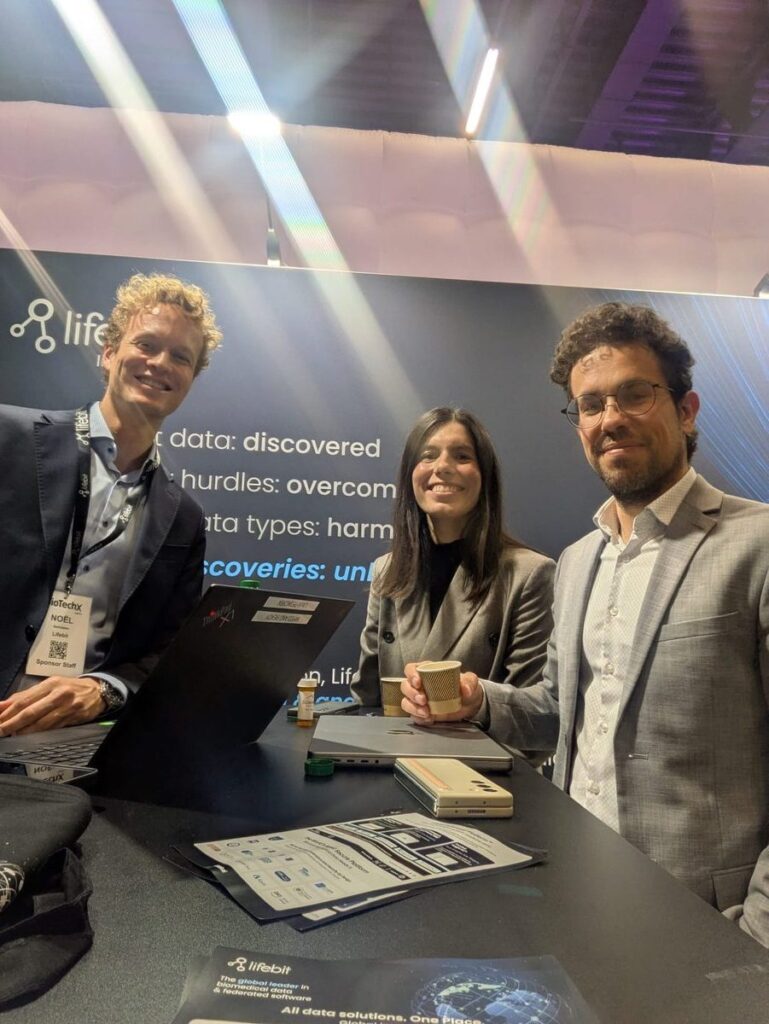 Three Lifebit colleagues smiling at the booth